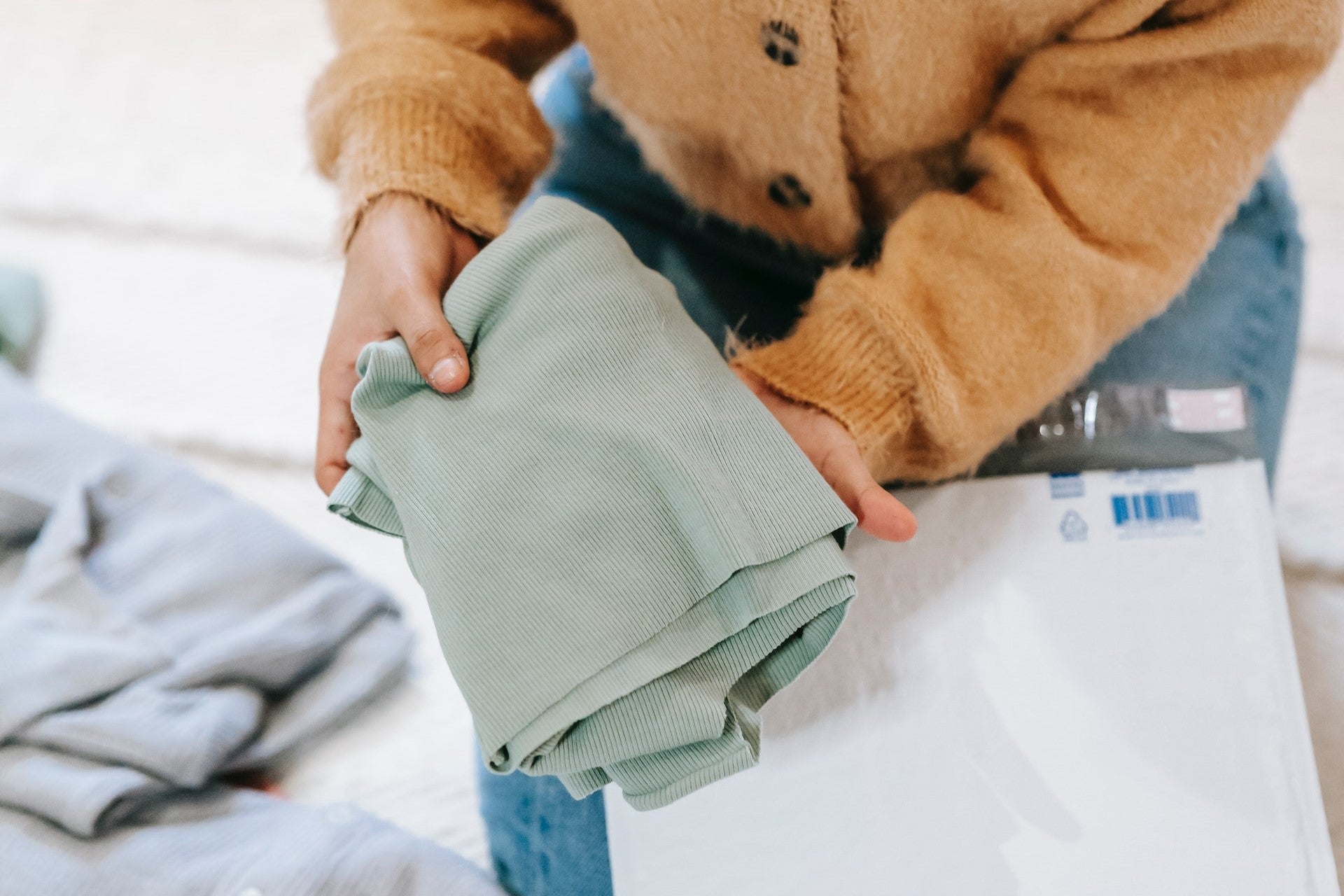 Person Placing Shirt Inside Poly Mailer